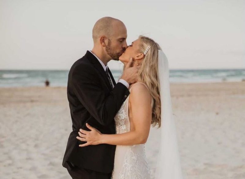 beach wedding hairstyles | bride and groom embrace on the beach